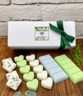 Collection of wax melts with a white box featuring a green ribbon on a wooden surface.